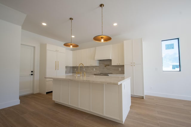 kitchen with decorative light fixtures, custom range hood, decorative backsplash, white cabinetry, and sink