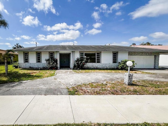 single story home featuring driveway, an attached garage, and stucco siding