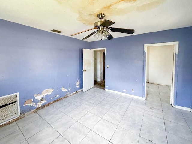 empty room featuring a ceiling fan, visible vents, and baseboards