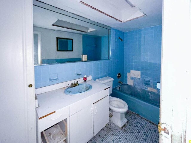 full bathroom with tile walls, decorative backsplash, toilet, vanity, and tiled shower / bath combo