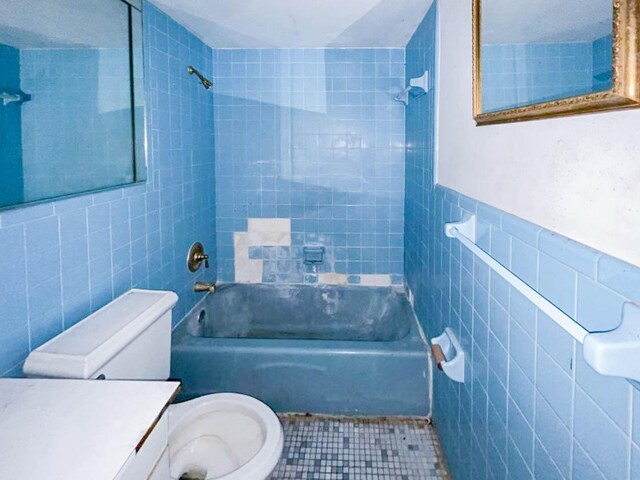 full bathroom with toilet, tiled shower / bath, and tile walls