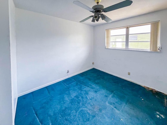 empty room featuring baseboards, dark carpet, and a ceiling fan