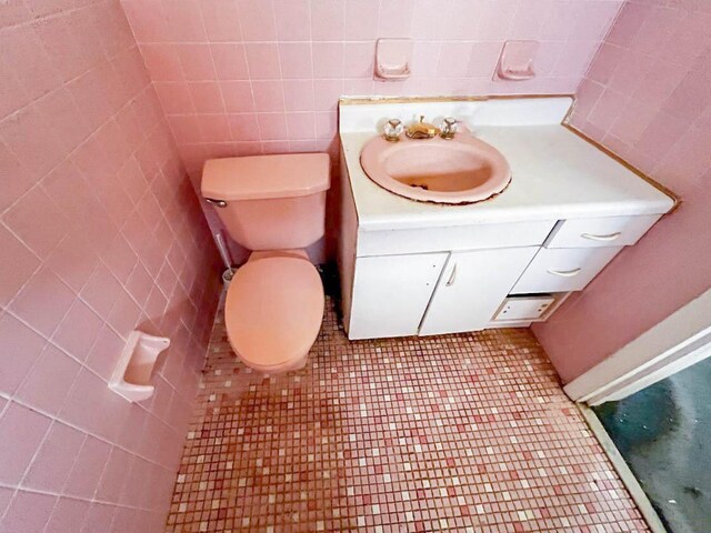 bathroom with tile walls, tile patterned floors, toilet, and vanity