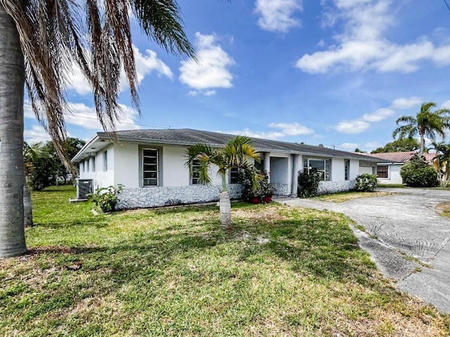 single story home with aphalt driveway, a front yard, central air condition unit, and stucco siding