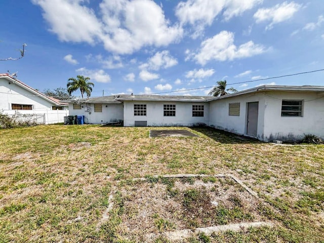 back of property featuring a lawn, fence, and stucco siding