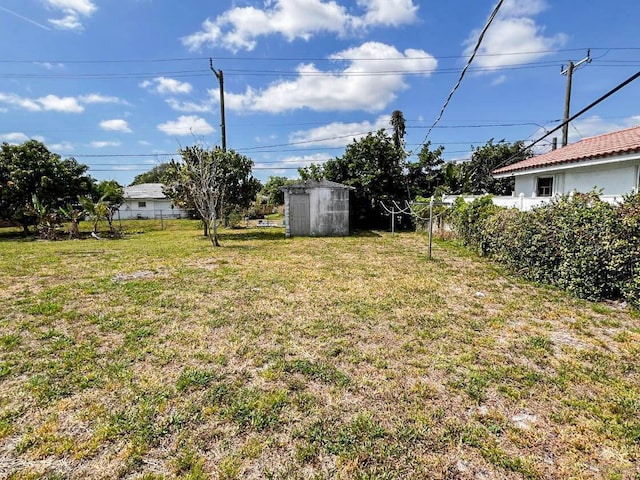 view of yard featuring an outbuilding, a shed, and fence