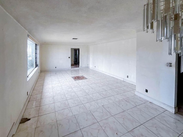 spare room with a textured ceiling and baseboards