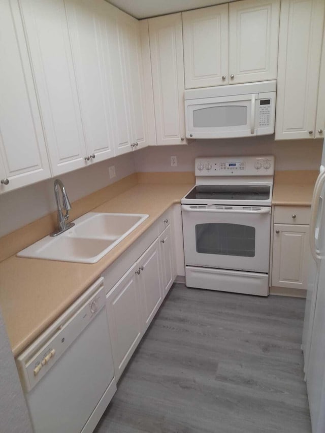 kitchen featuring sink, dark hardwood / wood-style flooring, white appliances, and white cabinets