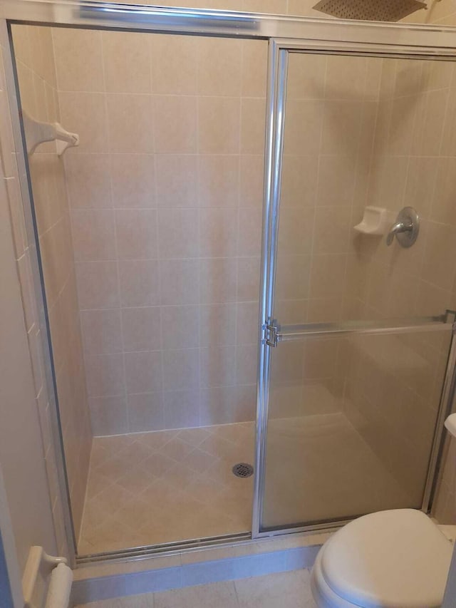 bathroom with a shower with shower door and toilet