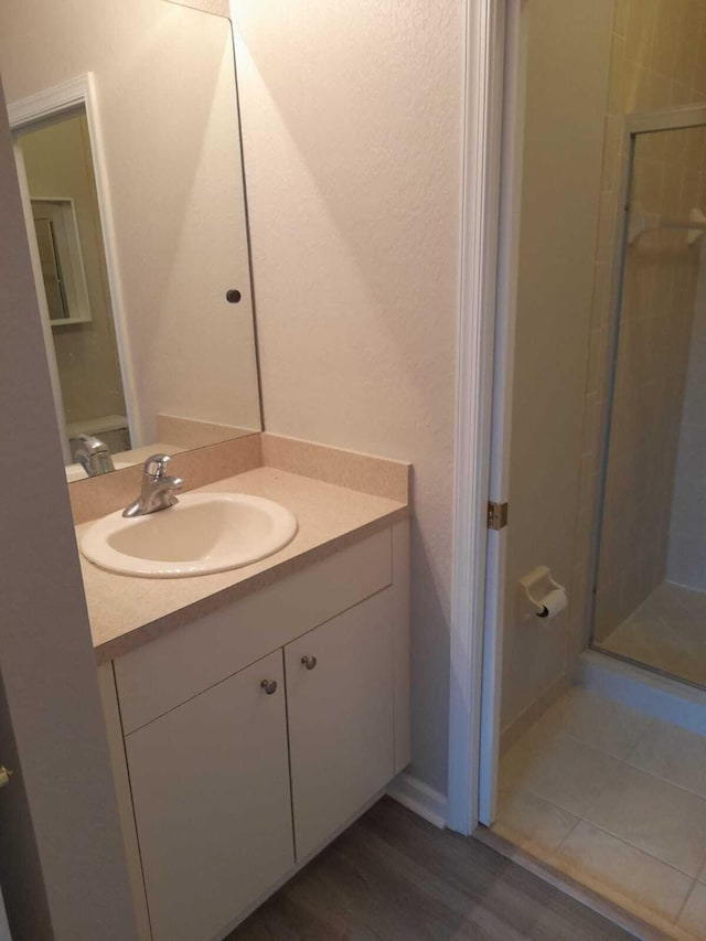 bathroom featuring vanity, wood-type flooring, and walk in shower