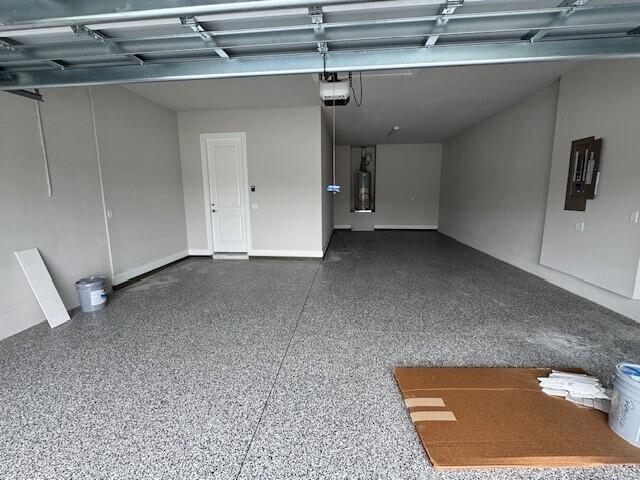 garage featuring water heater, a garage door opener, and electric panel