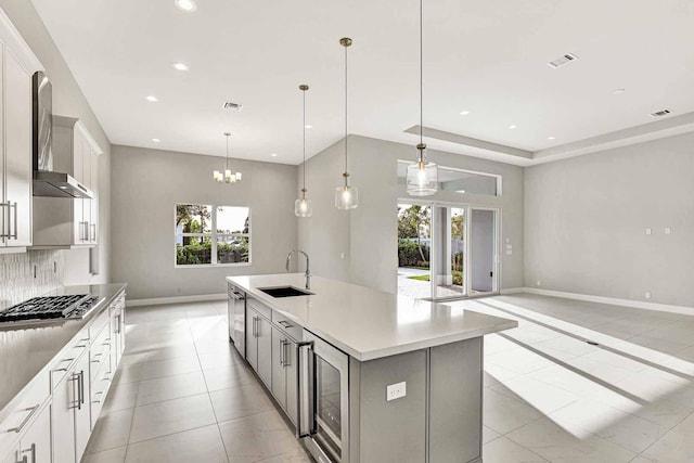 kitchen featuring appliances with stainless steel finishes, decorative light fixtures, sink, white cabinets, and a large island