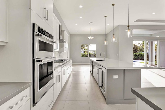 kitchen featuring white cabinetry, sink, hanging light fixtures, and a spacious island