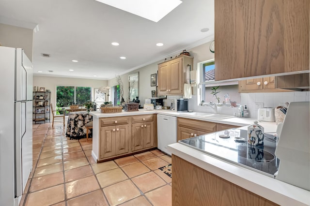 kitchen featuring white appliances, kitchen peninsula, light tile patterned floors, decorative backsplash, and light brown cabinetry