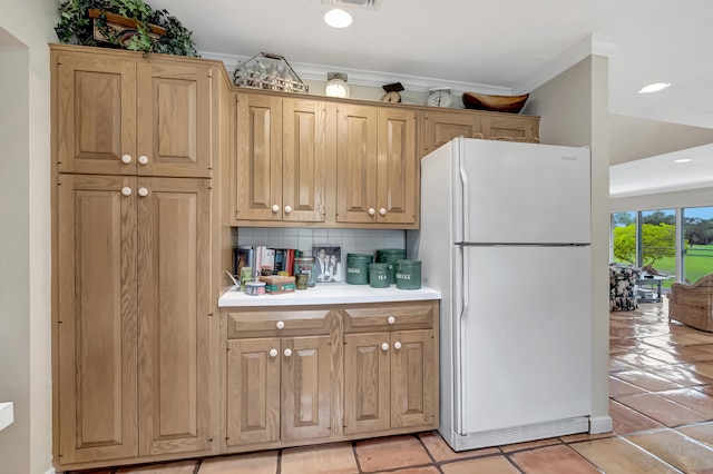 kitchen featuring backsplash, ornamental molding, white refrigerator, and light tile patterned floors