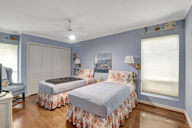 bedroom featuring a closet, multiple windows, ceiling fan, and light wood-type flooring