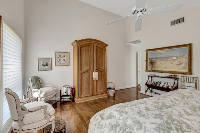 bedroom with dark hardwood / wood-style floors, ceiling fan, and a towering ceiling