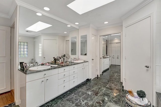 bathroom featuring a skylight, ornamental molding, tile patterned floors, and dual bowl vanity