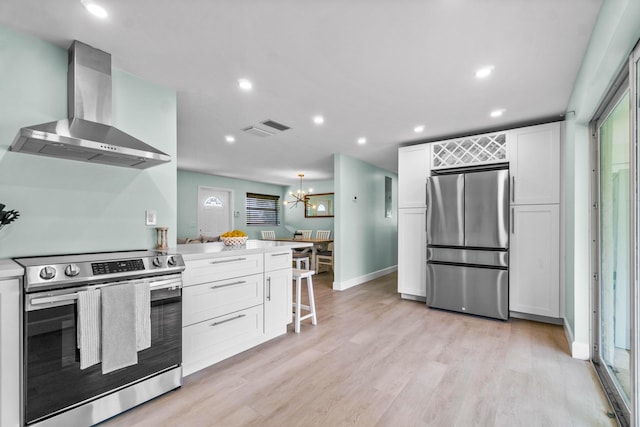 9531 Birdwood St, Palm Beach Gardens, FL 33410 - kitchen featuring appliances with stainless steel finishes, wall chimney range hood, white cabinetry, light wood-type flooring, and recessed lighting