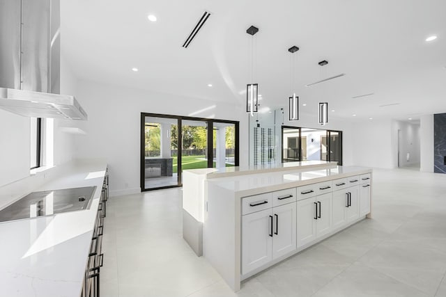 kitchen with pendant lighting, white cabinetry, a spacious island, light stone countertops, and black electric cooktop