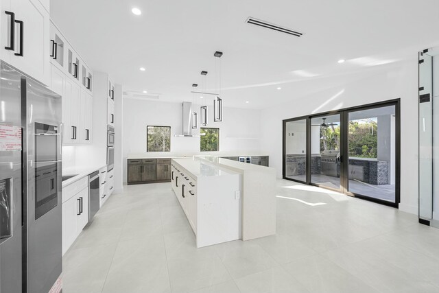 kitchen with pendant lighting, white cabinetry, a spacious island, light stone countertops, and black electric cooktop