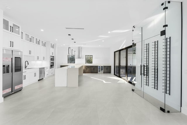 kitchen featuring a kitchen island, decorative light fixtures, sink, white cabinets, and stainless steel appliances