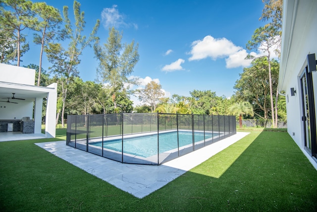 view of swimming pool with exterior kitchen, a patio area, and a lawn