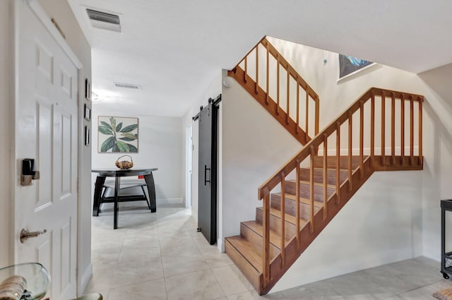 stairs with tile patterned floors and a barn door