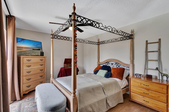 bedroom with a textured ceiling, hardwood / wood-style flooring, and ceiling fan