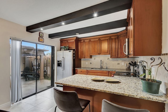 kitchen with sink, light stone countertops, appliances with stainless steel finishes, kitchen peninsula, and a breakfast bar area