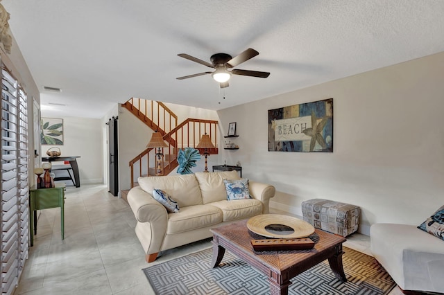 living room with ceiling fan and a textured ceiling