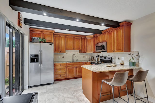 kitchen featuring sink, beamed ceiling, decorative backsplash, a breakfast bar, and appliances with stainless steel finishes