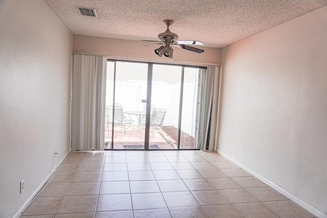 empty room featuring ceiling fan, light tile patterned flooring, a textured ceiling, and a healthy amount of sunlight