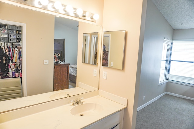 bathroom with vanity, vaulted ceiling, a textured ceiling, and plenty of natural light