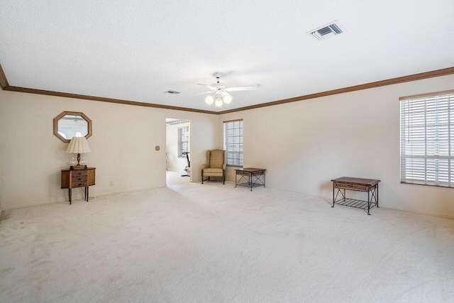 sitting room with ornamental molding, light carpet, ceiling fan, and a textured ceiling