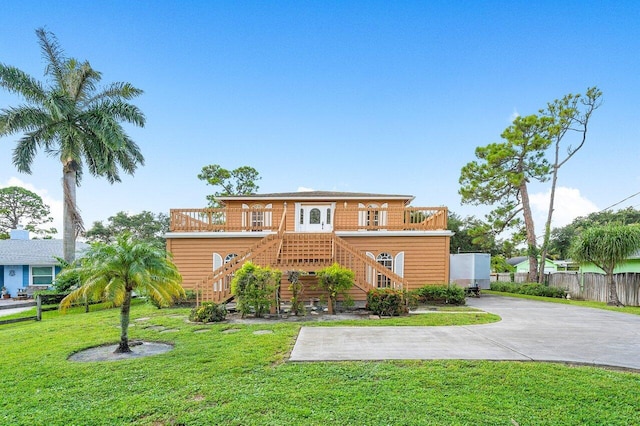 rear view of house with a wooden deck and a lawn