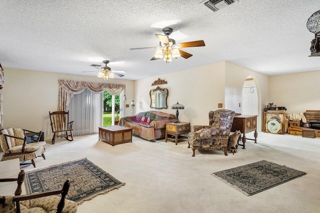 carpeted living room featuring ceiling fan and a textured ceiling