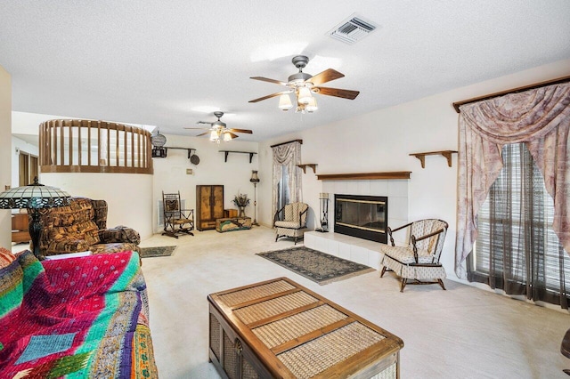 carpeted living room with ceiling fan, a tile fireplace, and a textured ceiling