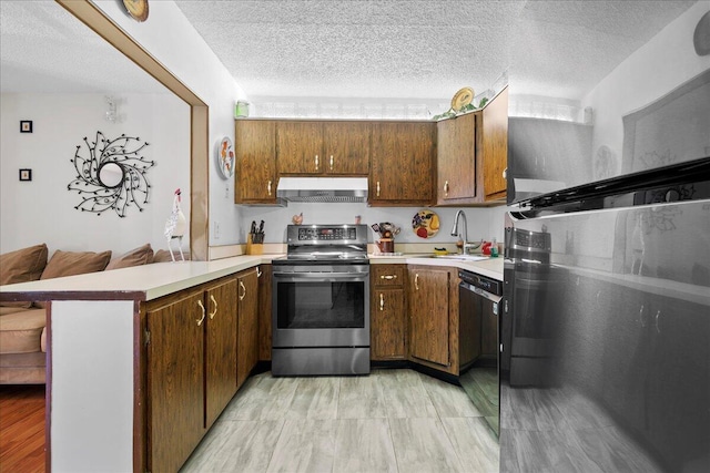 kitchen featuring stainless steel appliances, kitchen peninsula, sink, and a textured ceiling