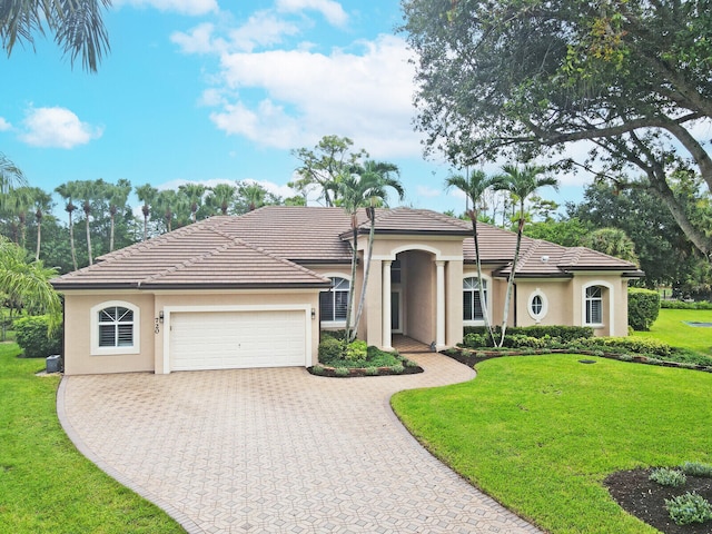 mediterranean / spanish house featuring a front yard and a garage