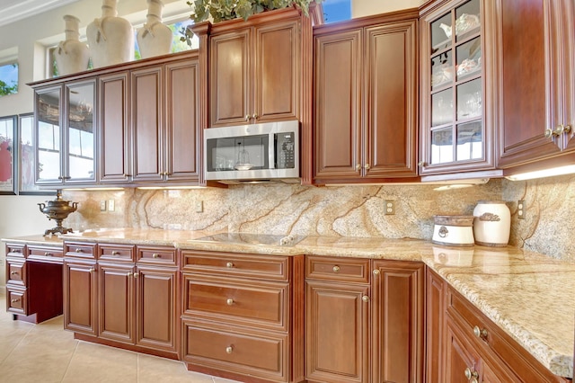 kitchen featuring decorative backsplash, light tile patterned flooring, light stone counters, and black electric stovetop