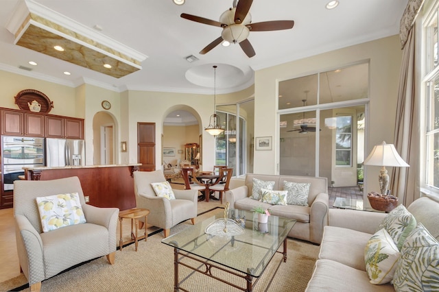 living room featuring crown molding, ceiling fan, and a healthy amount of sunlight