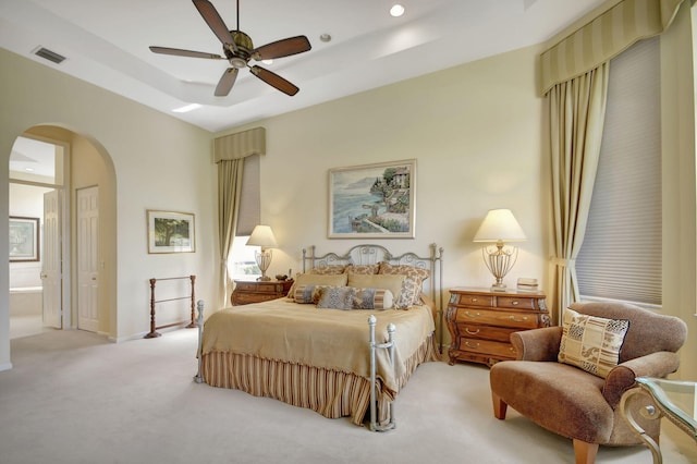 carpeted bedroom with connected bathroom, a raised ceiling, and ceiling fan