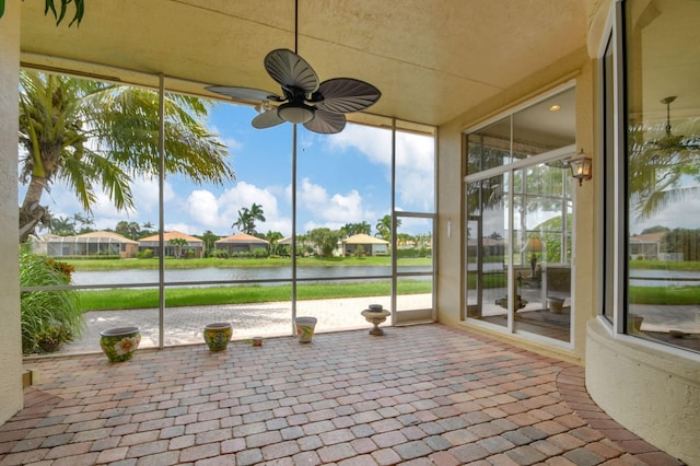 unfurnished sunroom with a water view and ceiling fan