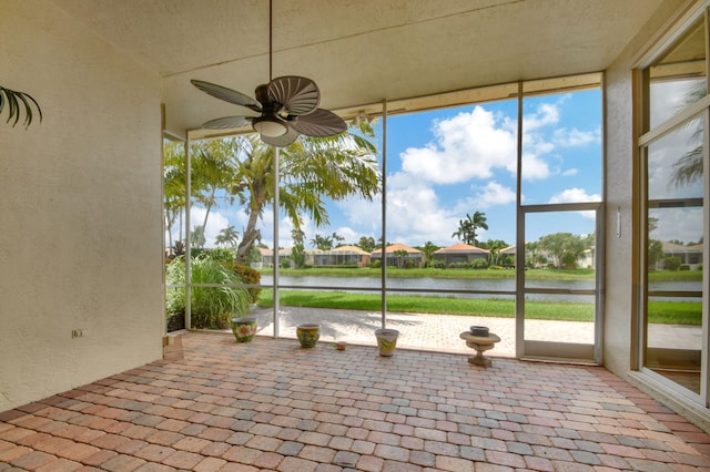 unfurnished sunroom featuring a water view and ceiling fan