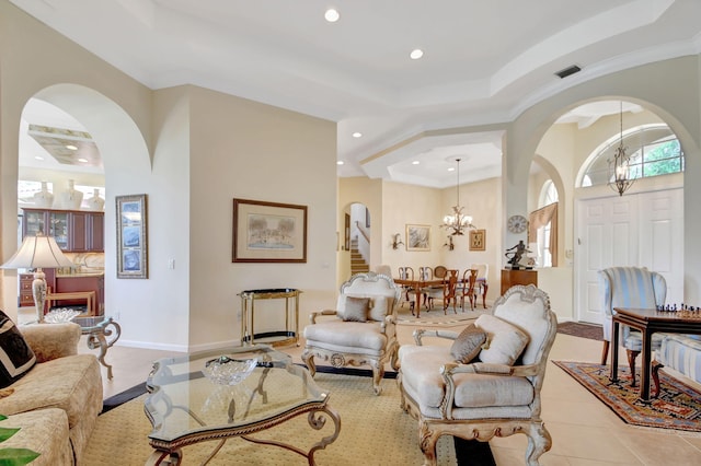 living room with tile patterned floors, a notable chandelier, and a tray ceiling