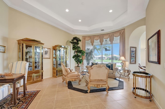 living room with ornamental molding, light tile patterned flooring, and a tray ceiling