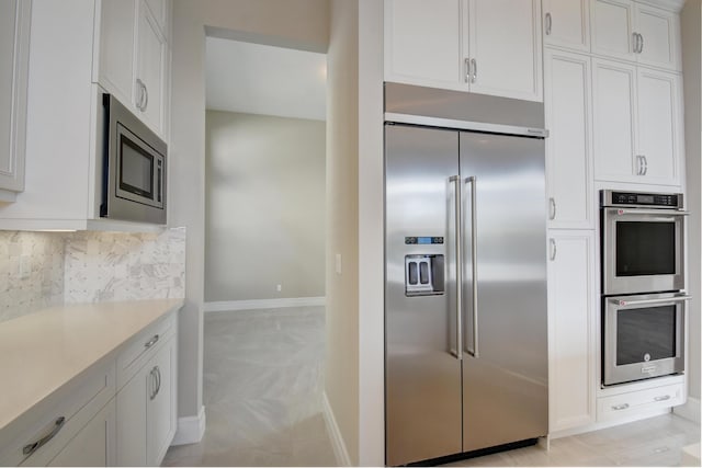 kitchen featuring tasteful backsplash, built in appliances, and white cabinets