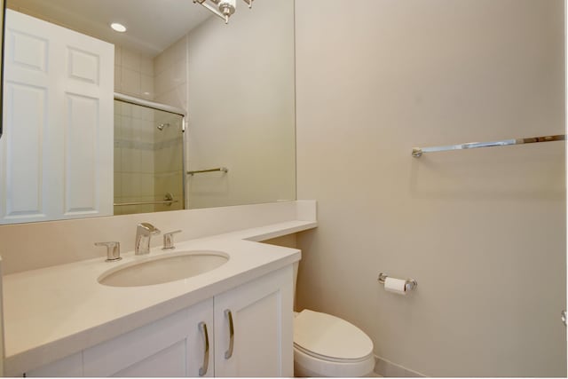 bathroom featuring vanity, toilet, and a shower with shower door