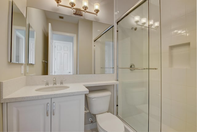 bathroom with an enclosed shower, vanity, and toilet